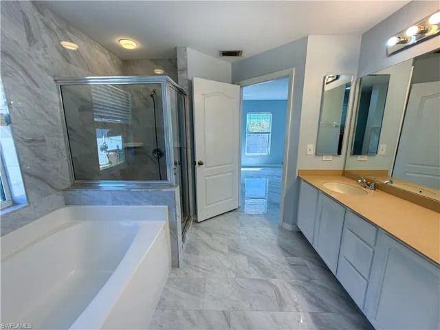 Bathroom with vanity, a shower stall, a bath, and light marble finish floors