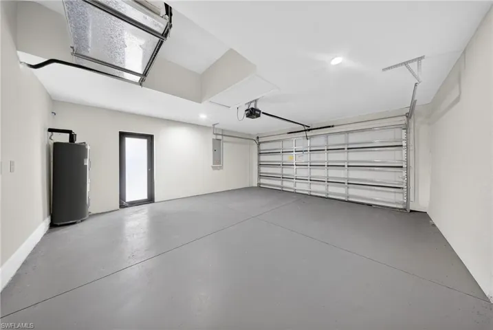 Garage with water heater, electric panel, and a garage door opener