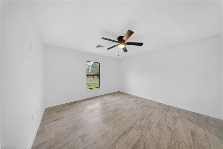 Empty room featuring a ceiling fan and baseboards