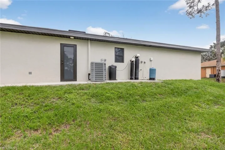 Rear view of property with stucco siding, a yard, and a patio