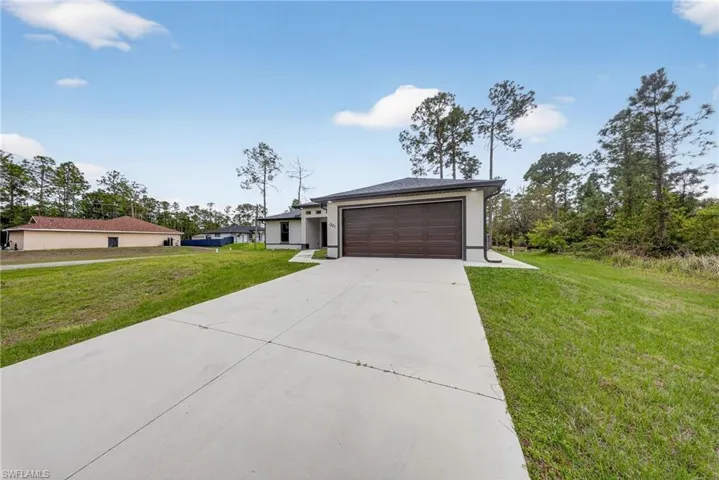 Prairie-style home featuring a front yard, driveway, a garage, and stucco siding