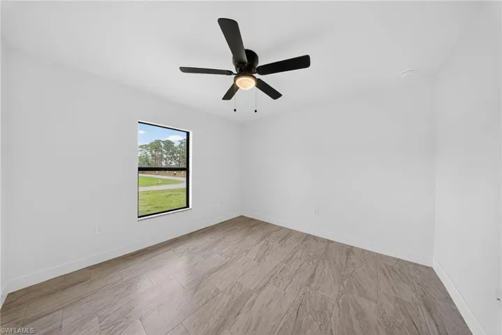 Unfurnished room with a ceiling fan and baseboards