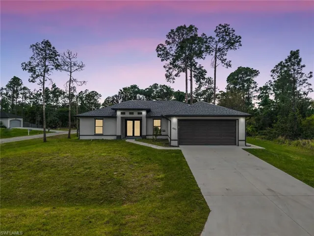 Prairie-style home featuring a front lawn, stucco siding, concrete driveway, and a garage