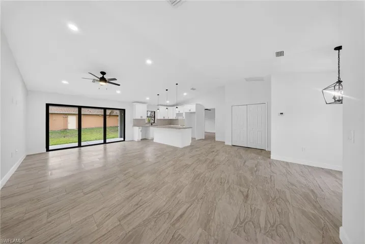 Unfurnished living room with a ceiling fan, vaulted ceiling, and recessed lighting