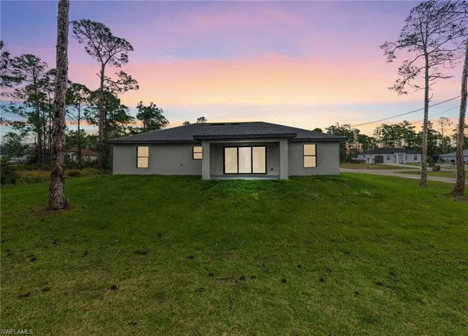 Rear view of property with stucco siding, a yard, and a patio area