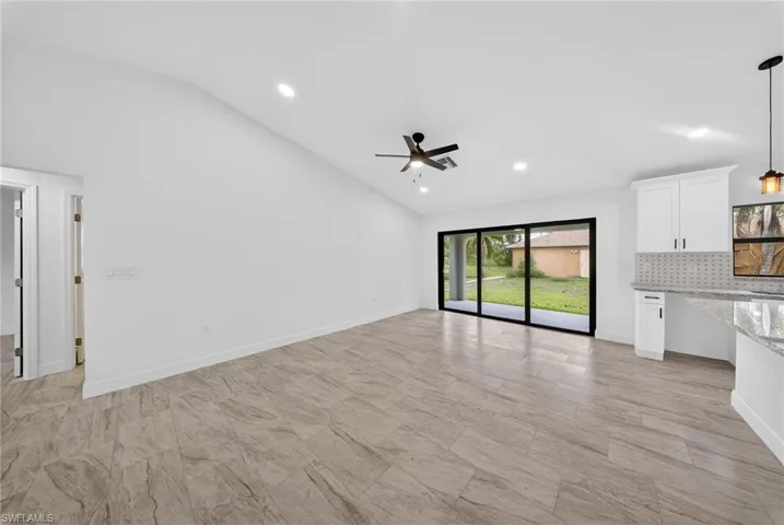 Unfurnished living room featuring vaulted ceiling, ceiling fan, and recessed lighting