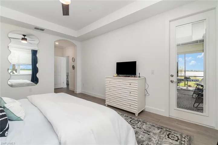 Bedroom with access to outside, wood finished floors, arched walkways, and ceiling fan