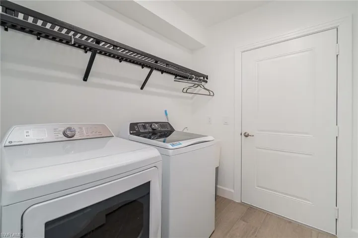 Laundry room with washing machine and dryer and light wood-style floors