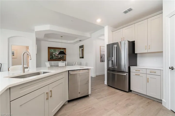 Kitchen featuring appliances with stainless steel finishes, arched walkways, light wood-style floors, light countertops, and recessed lighting