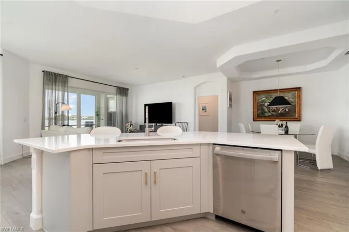 Kitchen with stainless steel dishwasher, light countertops, light wood-style flooring, and open floor plan