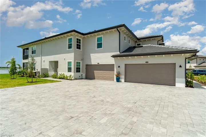View of front of house featuring stucco siding, decorative driveway, a front yard, and an attached garage