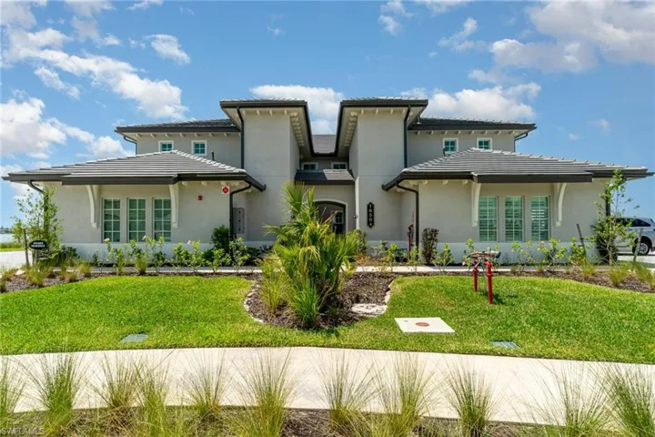 View of front facade featuring stucco siding, a front lawn, and a tiled roof
