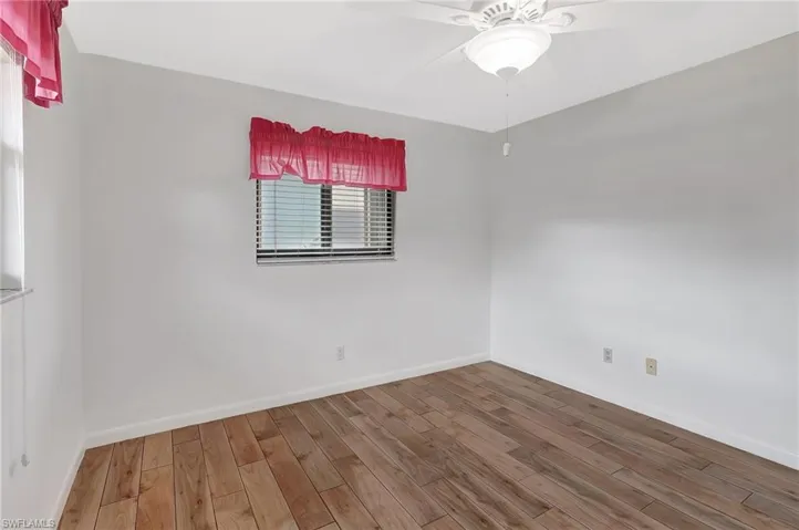 Spare room with wood finished floors, ceiling fan, and baseboards