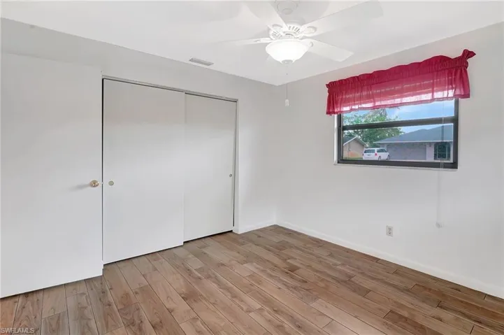 Unfurnished bedroom featuring light wood-style flooring, a closet, baseboards, and a ceiling fan