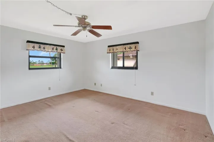 Empty room featuring carpet, baseboards, and a ceiling fan