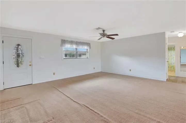 Foyer with light colored carpet, ceiling fan, and baseboards