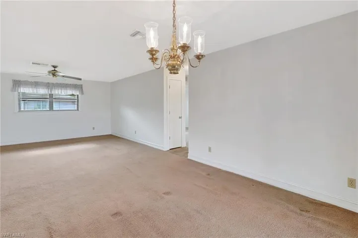 Carpeted spare room featuring a chandelier, ceiling fan, baseboards, and lofted ceiling