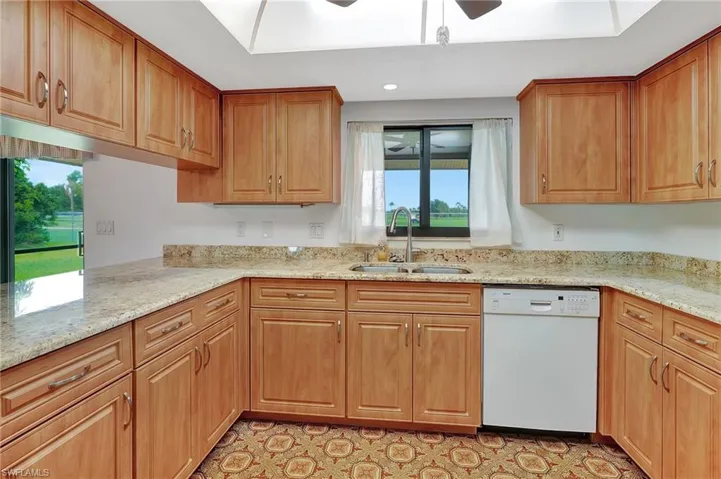 Kitchen with dishwasher, a sink, plenty of natural light, light stone countertops, and recessed lighting