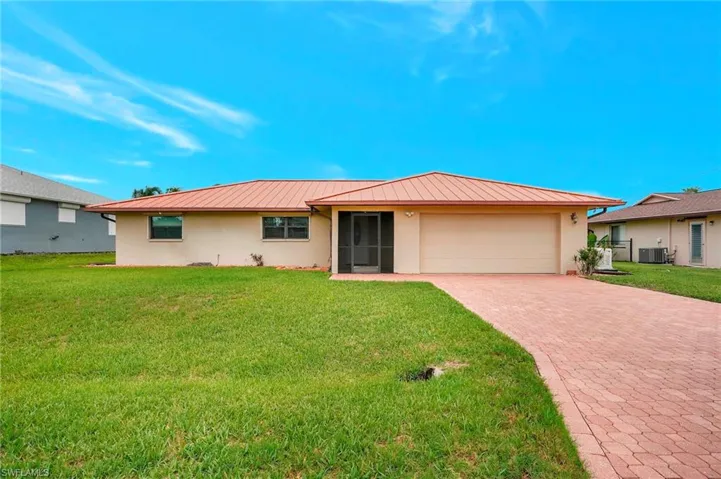 Ranch-style home featuring a standing seam roof, stucco siding, metal roof, decorative driveway, and a garage