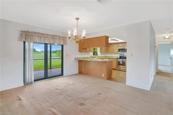 Kitchen with appliances with stainless steel finishes, baseboards, and light colored carpet