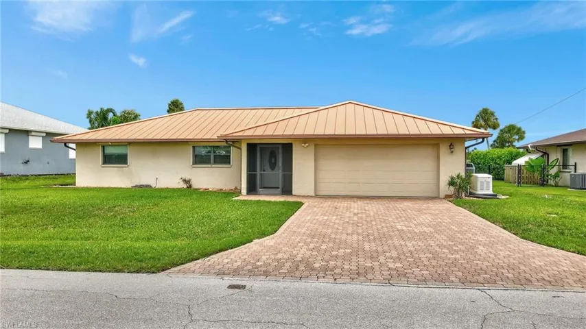 Ranch-style home featuring stucco siding, decorative driveway, an attached garage, metal roof, and a standing seam roof