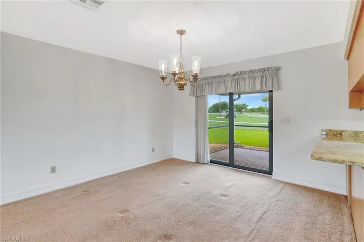Unfurnished dining area featuring a chandelier, light carpet, and baseboards