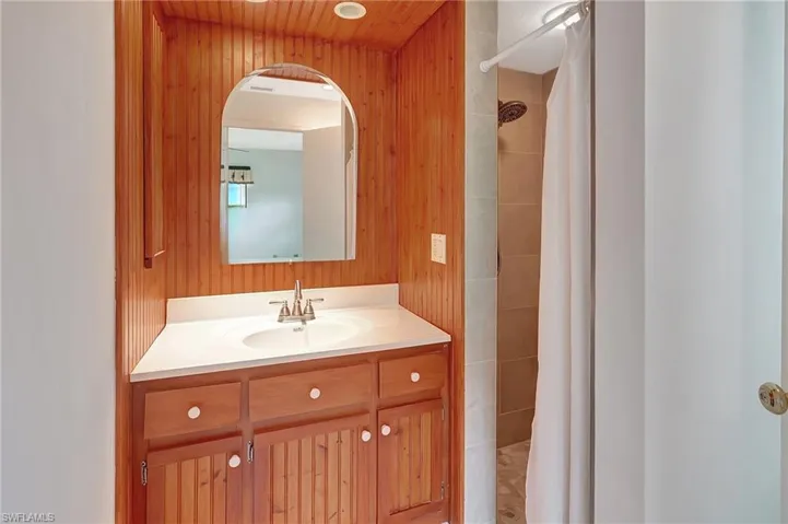 Bathroom featuring vanity, tiled shower, and wooden walls