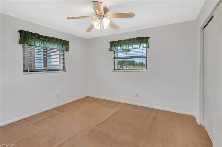 Spare room with light colored carpet, baseboards, and ceiling fan