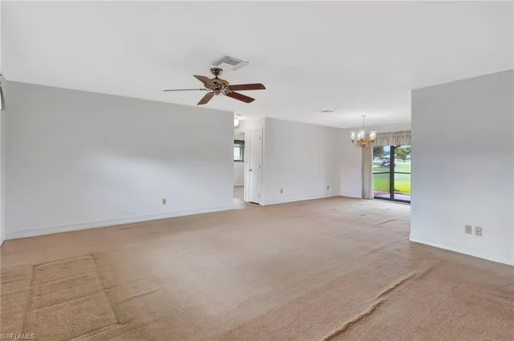 Empty room with a chandelier, baseboards, a ceiling fan, and light colored carpet