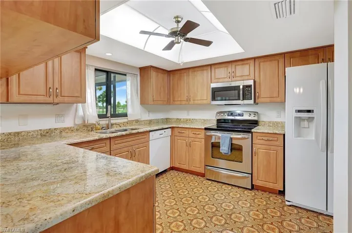 Kitchen featuring appliances with stainless steel finishes, a sink, ceiling fan, recessed lighting, and light stone countertops