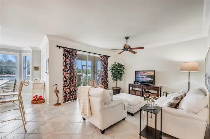 Tiled living area featuring ornamental molding and ceiling fan