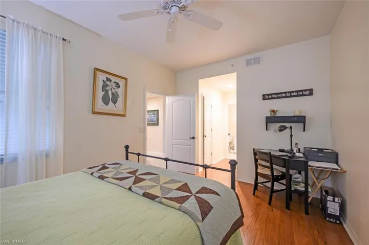 Bedroom featuring wood finished floors, ceiling fan, and ensuite bath