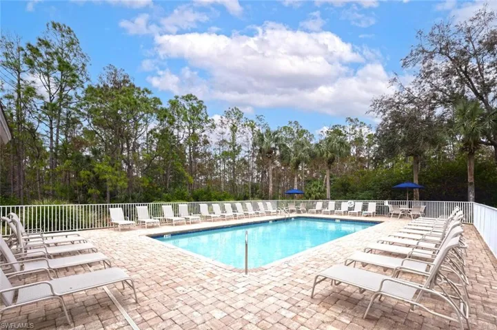 Community pool featuring a patio and view of wooded area