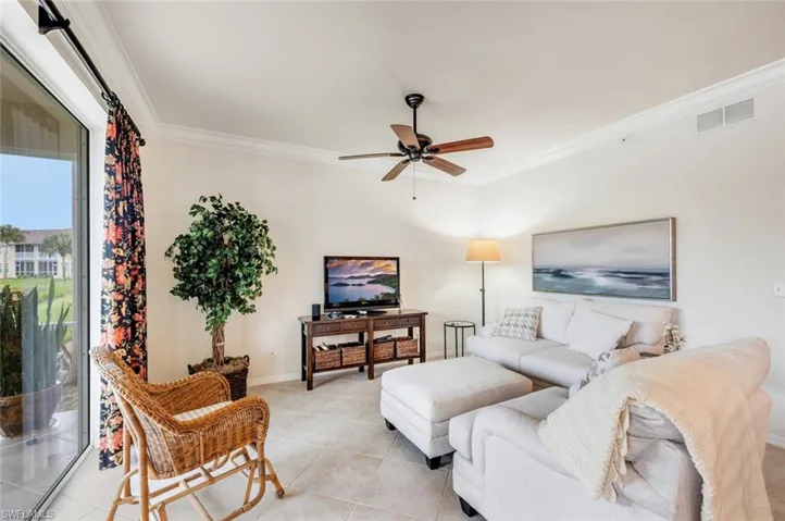 Living room featuring ornamental molding, ceiling fan, and light tile patterned floors