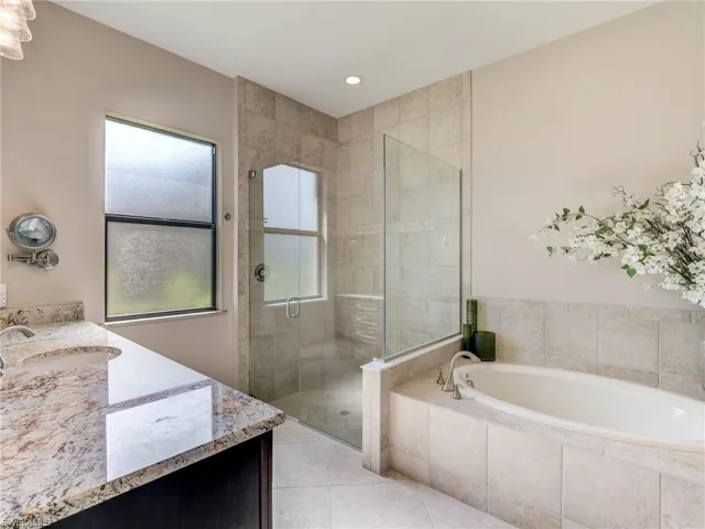 Full bath featuring vanity, a shower stall, a garden tub, light tile patterned floors, and recessed lighting