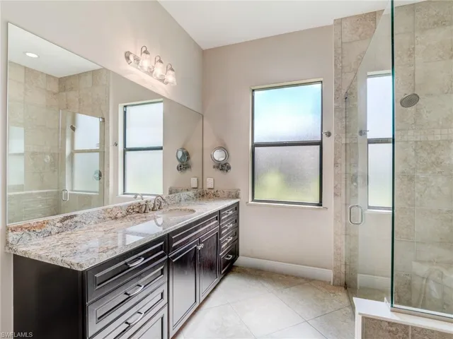 Full bathroom featuring a shower stall, vanity, and light tile patterned floors