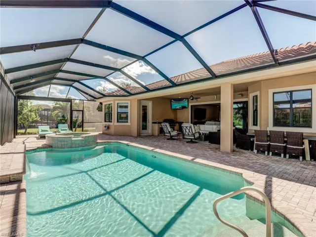 View of pool, outdoor lounge area, a patio, screened enclosure, and a pool with connected hot tub