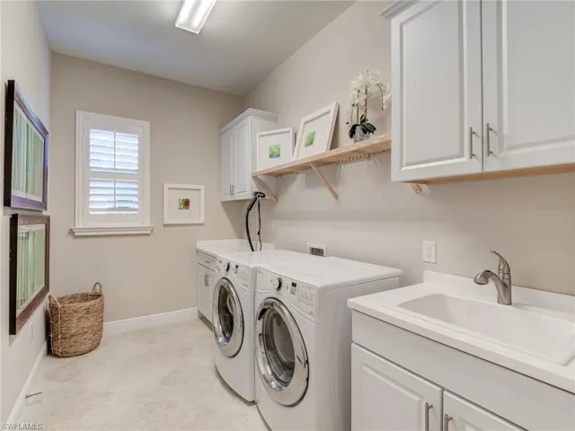 Laundry area featuring cabinet space, washing machine and clothes dryer, and sink.