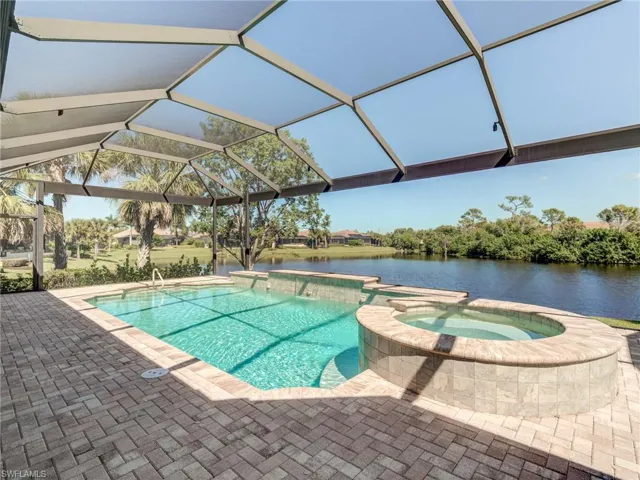 View of pool with a patio, a pool with connected hot tub, a lanai, and a water view.