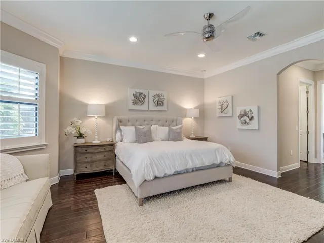 Bedroom featuring crown molding, arched walkways, dark wood-style floors, recessed lighting, and ceiling fan