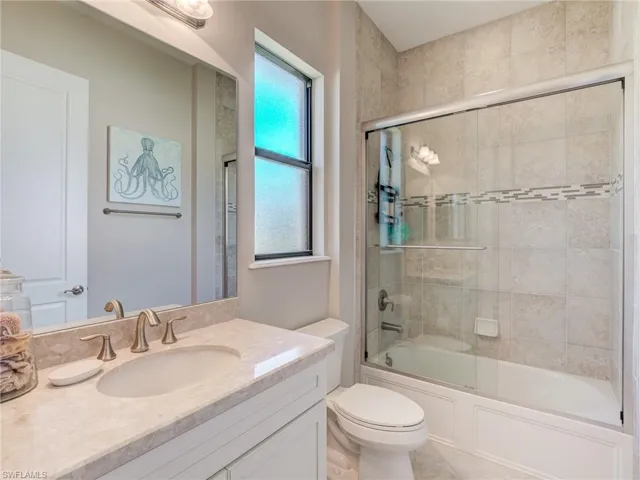 En Suite Bathroom featuring bath / shower combo with glass door and vanity