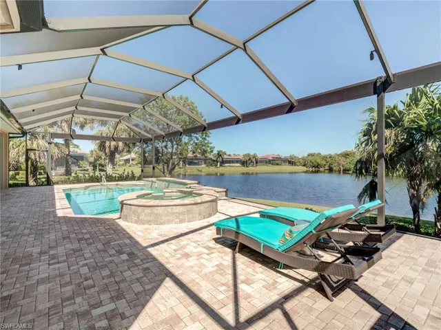 View of pool with a patio, a lanai, a pool with connected hot tub, and a water view