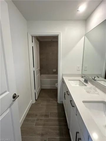 Full bathroom featuring dual vanity, toilet, and tiled shower / bath