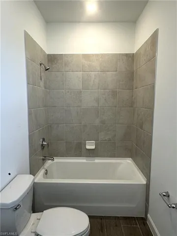Bathroom featuring tiled shower / bath combo, hardwood / wood-style flooring, and toilet