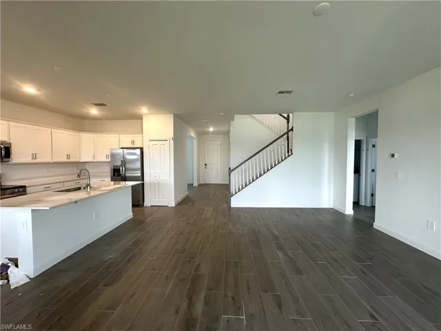Kitchen with appliances with stainless steel finishes, sink, dark hardwood / wood-style flooring, and white cabinets