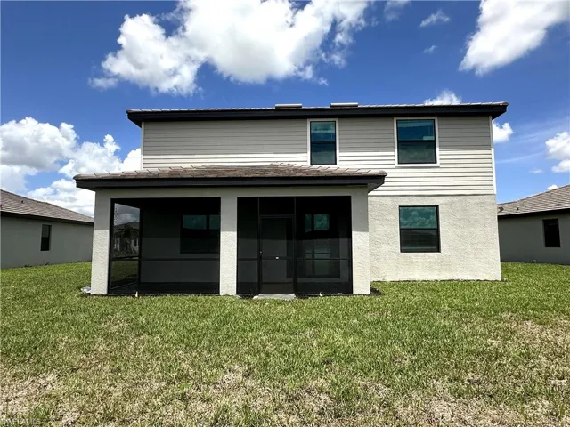 Rear view of house featuring a yard and a sunroom