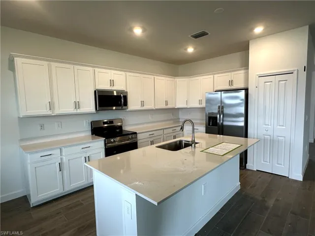 Kitchen featuring sink, appliances with stainless steel finishes, dark hardwood / wood-style flooring, and white cabinets