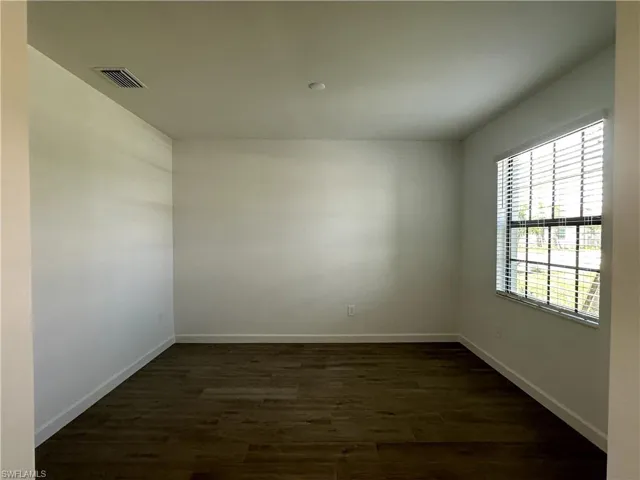 Empty room with dark hardwood / wood-style flooring