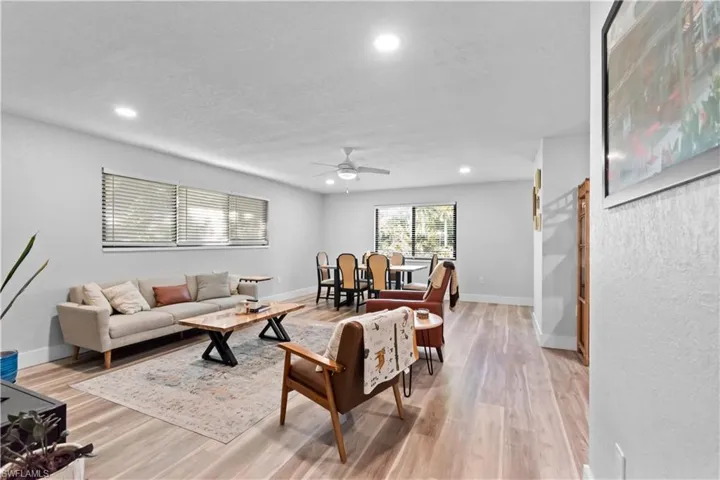 Living area with recessed lighting, ceiling fan, light wood-style floors,