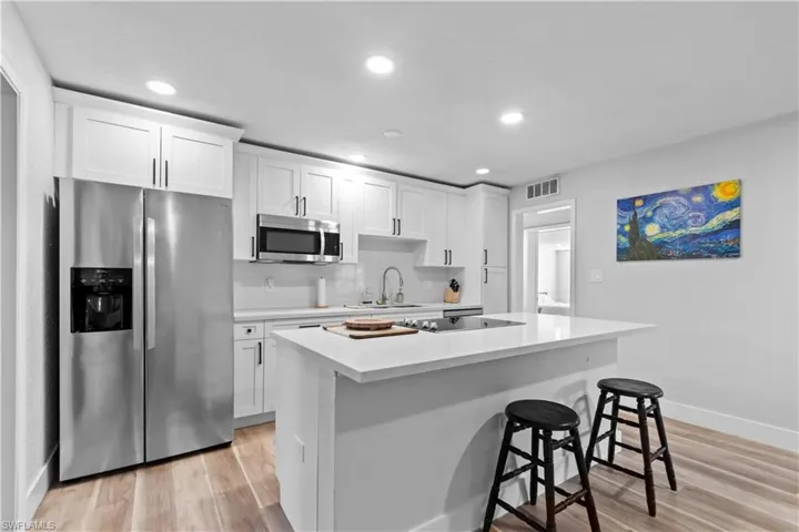 Kitchen featuring appliances with stainless steel finishes, white cabinetry, recessed lighting, light LVP flooring throughout